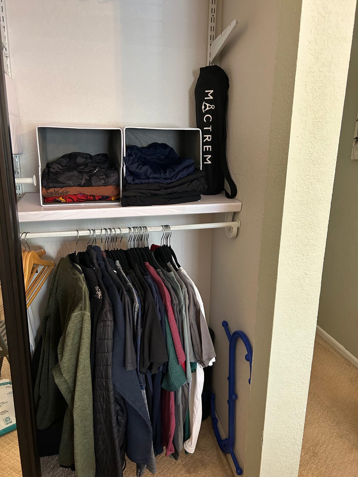 Closet after — floor clear, jackets hung, folded clothes in bins