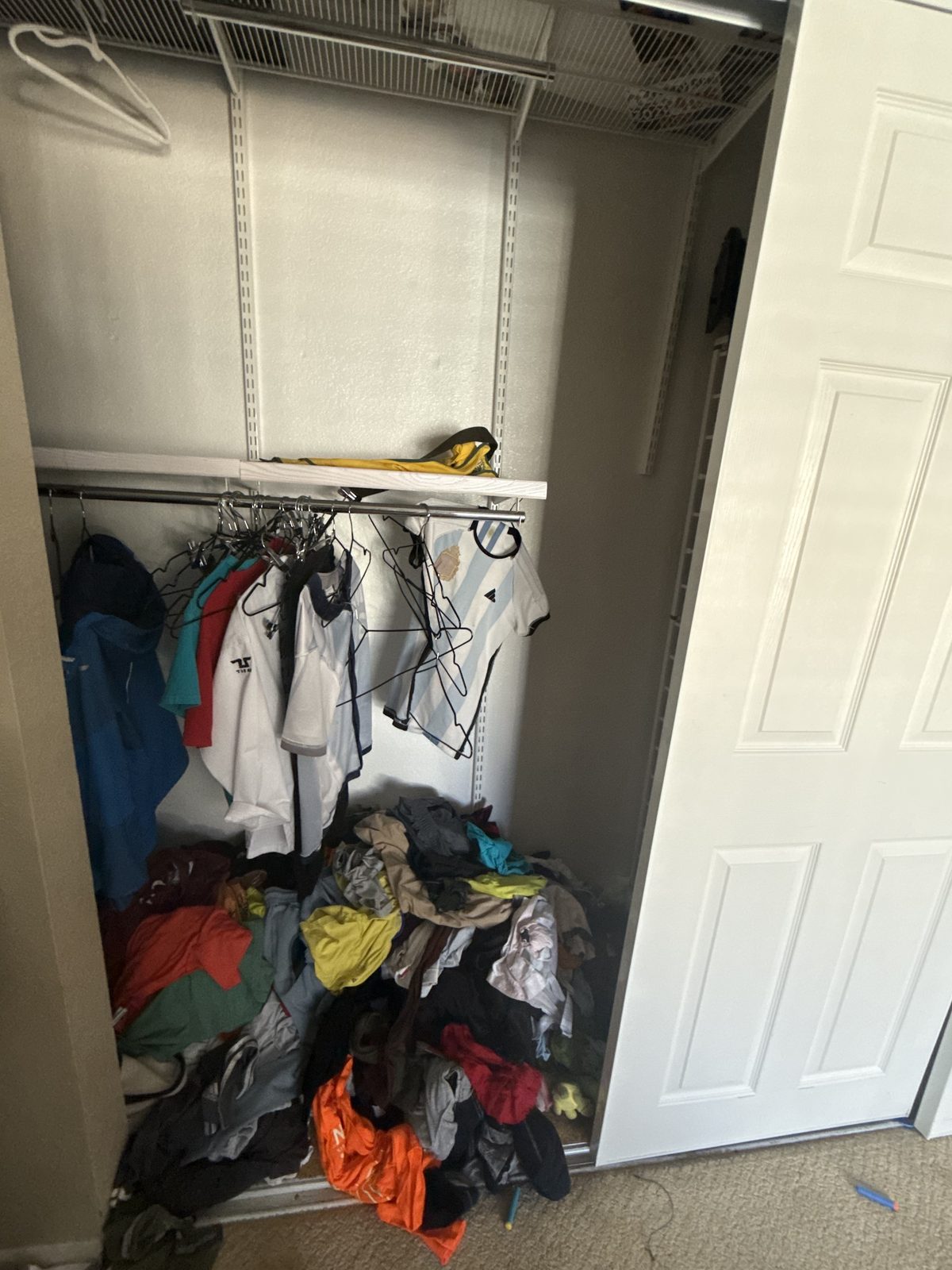 Closet before — a large pile of clothes on the floor below the rod