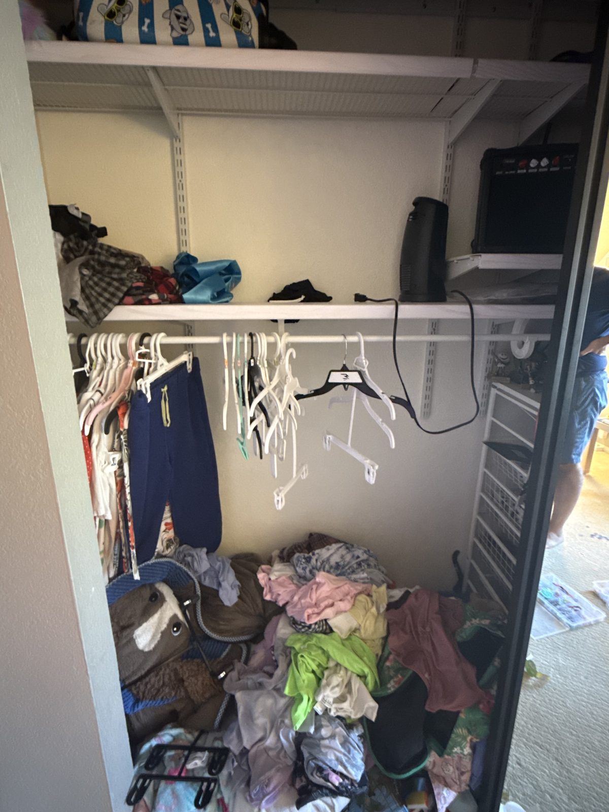 Girl's closet before — clothes piled on the floor, empty hangers on the rod
